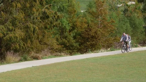 Houston TX Oct 2017 Couple Riding Bikes in Park Down Walkway Stock Footage 83966819