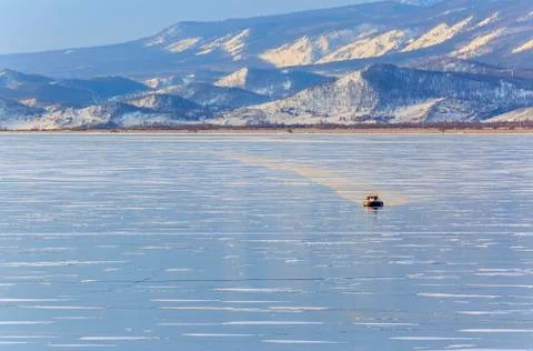 A hovercraft rides on the ice with mountains in the background Stock Photos