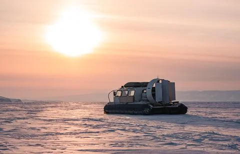 Hovercraft standing on snow covered ice surface of Lake Baikal at dusk. 스톡 사진