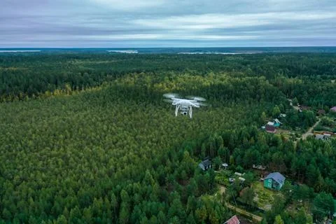 Hovering drone in the white sky over the forest, blue sky with w Stock Photos