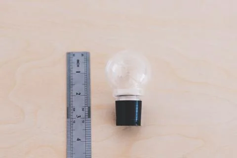 How big are your ideas, lightbulb on desk next to ruler Stock Photos