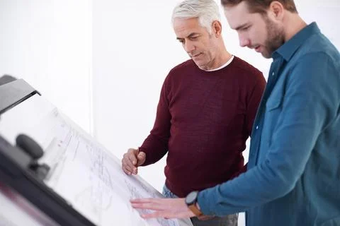 How can we open this up a bit. two male architects working on a building plan at Fotos de archivo