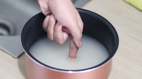 How to cook rice. Use your finger to measure the water level when cooking rice Stock Footage 316033214