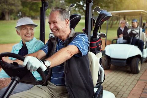 How could golf ever be boring. a smiling senior couple riding in a cart on a Fotos Stock