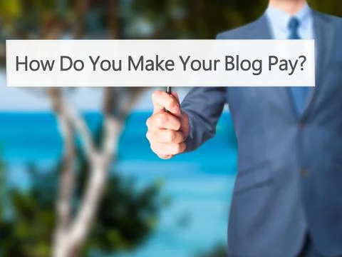 How Do You Make Your Blog Pay - Businessman hand holding sign Stock-Fotos