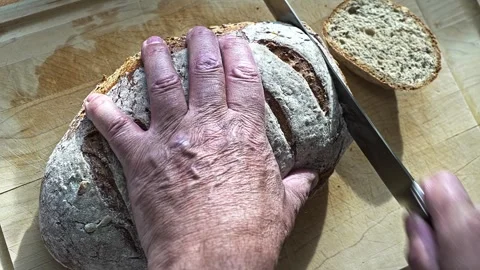How to slice loaf bread using a knife on a wooden cutting board Stock Footage 324441479