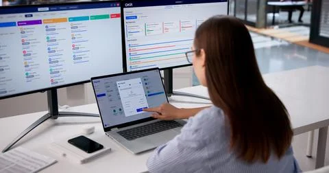 HR Manager Checks Payroll Data On Multiple Screens To Ensure Accuracy. Stock Photos