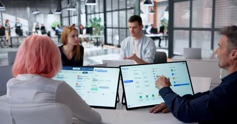 HR Manager Checks Payroll Software Carefully On Tablet During Team Meeting. Stock Photos