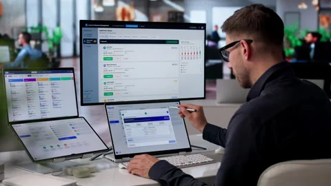 HR Manager Reviews Payroll Software On Dual-screen Laptop Stock Footage 340995302