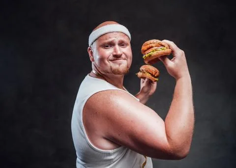 Hubby but strong men pulling a face with two hamburgers in his hands Stock Photos