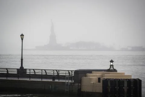 Hudson river docks under the rain overlooking the Statue of Liberty from the Stock Photos