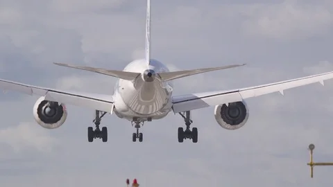 Huge airplane rear view landing on runway behind landing poles lamps Stock Footage 78966246