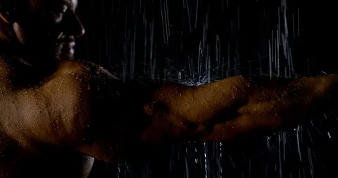 A huge bald athletic man stretched out his muscular arm. he watches the rain Stock Footage 118768919