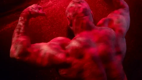 A huge bald man with a beard demonstrates the muscles of back in dark water. red Stock Footage 179310325