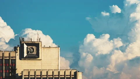 Huge blue-white cumulus cloud floats behind a high building with symbols of a Stock Footage 136741365