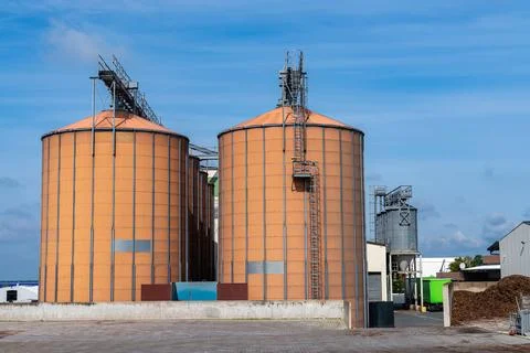 Huge brown elevators for storing grain under a blue sky. Stock Photos