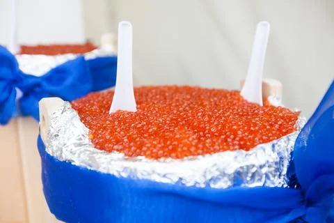 Huge bucket of red caviar on table Фото