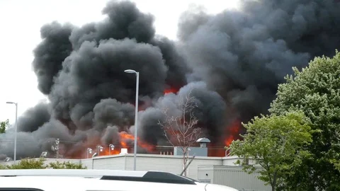 Huge building fire sends large flames up in the air on a windy day Vidéo 97687438