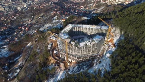 A huge building under construction in the forest. Cranes on construction site. Stock Footage 303673807