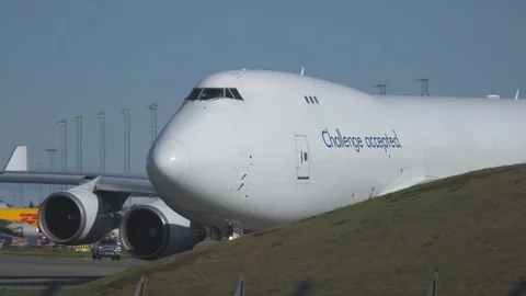 Huge cargo airplane boeing 747 taxiing behind obstacles turning Stock Footage 115953094