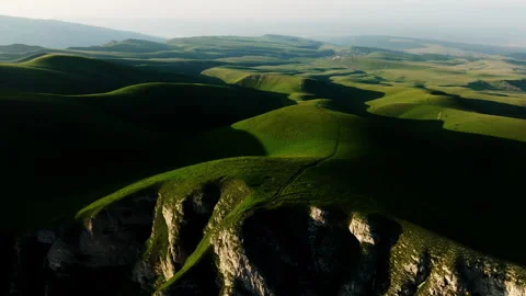 A huge clearing of mountain hills covered with green grass in the backlit sun. Stock Footage 257515972