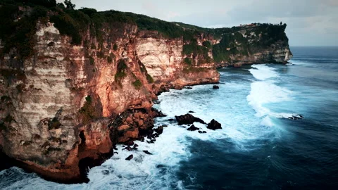 Huge cliffs in the sunset with waves crashing in Stock Footage 250070287