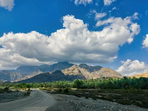A huge cloud casts a dark shadow on a huge mountain range in Oman. 写真素材