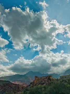 Huge clouds cast a shadow on an old fort constructed on the edge of a mountai 스톡 사진