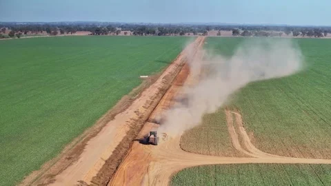 Huge clouds of dust come off a tractor pulling a small road grader on farm Stock Footage 276971462