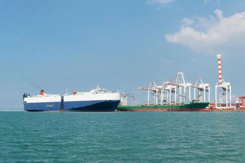 Huge container cargo ship is going to harbor with blue sky background Stock Photos
