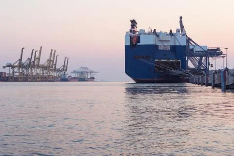 Huge container cargo ship on harbor while load car into it Stock Photos