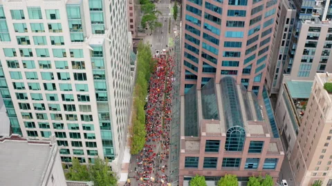 Huge crowd of protesters moving below, pull back tilt aerial in a major Stock Footage 157149251