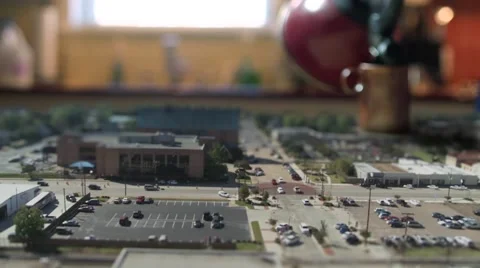 A huge cup of tea gets poured over a miniature tilt shift city. Stock Footage 40005639