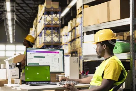 Huge distribution center worker verifying parcel details with isolated display Stock Photos
