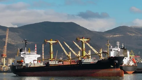 A huge empty cargo ship sails from the pier from the port of industrial city Stock Footage 102683773