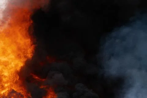 Huge flames of red fire, motion blur clouds of dark smoke covered sky Stock-Fotos