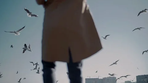 A huge flock of white gulls fly past the girl Stock Footage 89368394