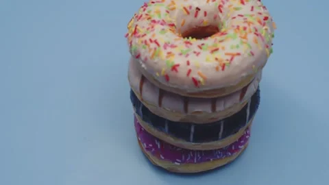 Huge fresh donuts with colored glaze and multicolored sprinkles lie on top of Stock Footage 200739157
