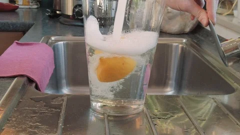Huge glass half filled with lemons is getting filled up - slow motion Stock Footage 104974134