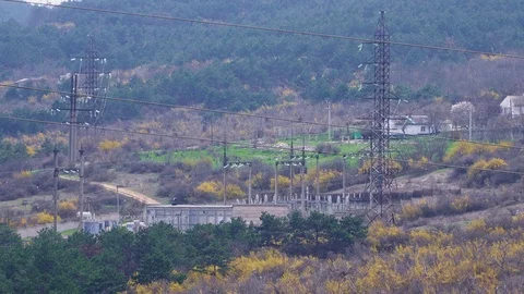 Huge high-voltage electrical supports, wires with electricity lead to the town Stock Footage 105637863