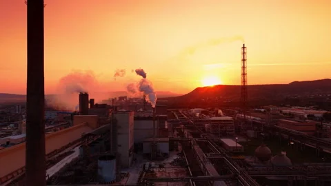 Huge industrial facility lit by the setting sun. Pipes of the plant produce Stock Footage 340856920
