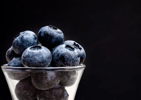 Huge juicy fresh blueberries in the small glass with black background. close-up  Stock Photos