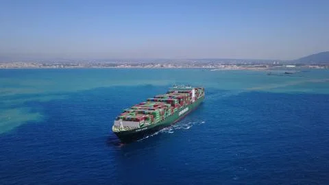 Huge large mega ULCV container ship sails on open water fully loaded Stock Photos