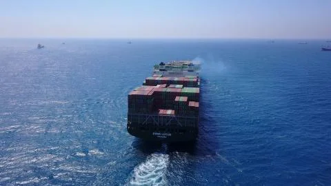 Huge large mega ULCV container ship sails on open water fully loaded Stock Photos