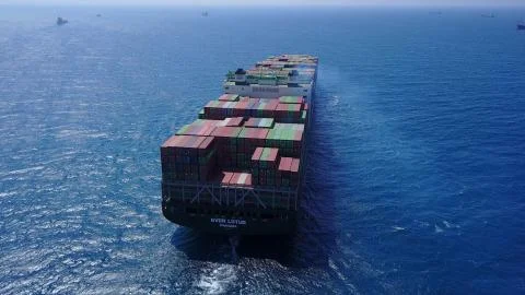 Huge large mega ULCV container ship sails on open water fully loaded Stock Photos