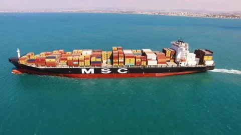 Huge large mega ULCV container ship sails on open water fully loaded Stock Photos
