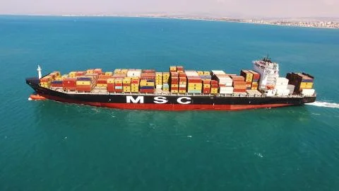 Huge large mega ULCV container ship sails on open water fully loaded Stock Photos