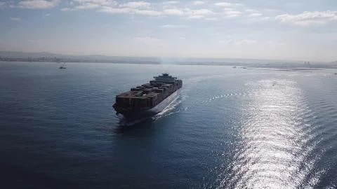 Huge large mega ULCV container ship sails on open water fully loaded Stock Photos