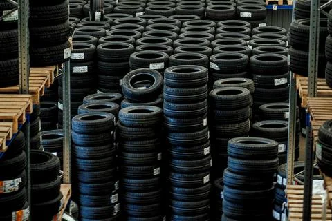Huge logistics warehouse filled with rows of brand new car tires on pallets.. Stock Photos