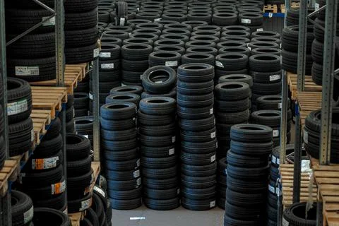 Huge logistics warehouse filled with rows of brand new car tires on pallets.. Stock Photos